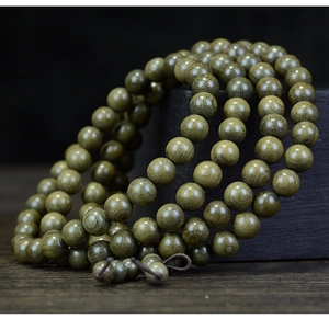 Macro shot of 108 Phoebe zhennan beads featuring natural wood grain on a wooden stand