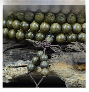 Macro detail of 108 ebony wood prayer beads with natural grain on rustic bark