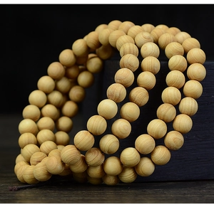 Macro shot of 108 polished Thuja wood beads showing natural circular grain textures