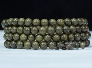 Macro detail of natural wood texture and oily sheen on 108 ebony prayer beads