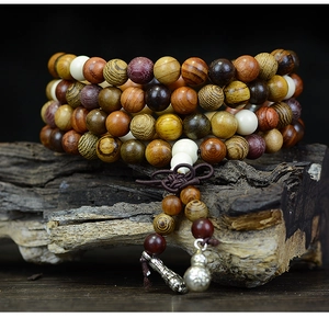 Macro shot of multi-wood 108 prayer beads with metal charms on a zen wooden base