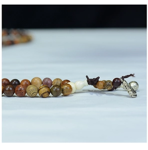 Detail of multi-colored wooden prayer beads featuring Buddha head and metallic animal charm