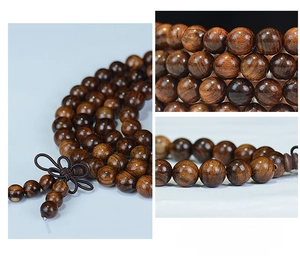 Macro shot of 108 black rosewood prayer beads featuring intricate knot and wood grain