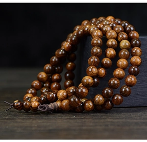 Detailed macro view of 108 dark brown rosewood prayer beads with natural wood grain texture