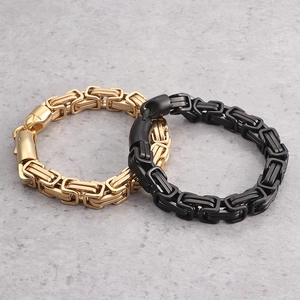 Men's titanium steel Byzantine chain bracelet in gold and black on a textured surface
