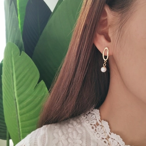 Detail view of gold 925 silver earring with shell pearl on model with white lace top