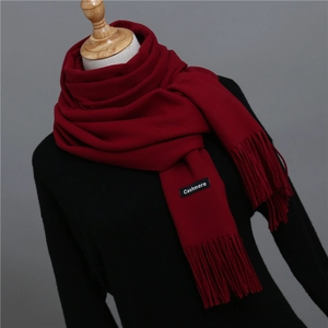 Macro shot of dark red cashmere scarf texture with tassel detail and fabric label