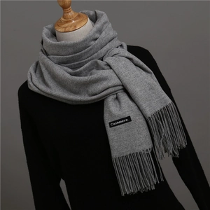 Detail shot of a grey cashmere scarf with thick tassels and authentic material tag