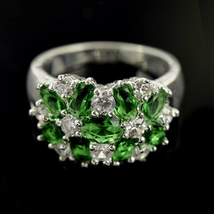 Dettaglio macro di anello in argento con gemme verdi ovali e zirconi scintillanti