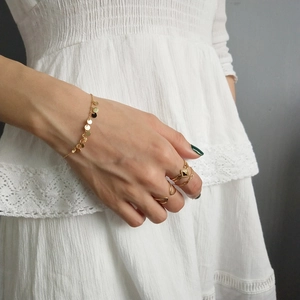 Close-up of elegant gold disc bracelet and geometric rings set worn by a female model
