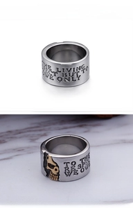 Detail of silver biker ring with golden skull accent and motivational engraving