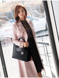 Close-up of black leather tote bag with maple leaf charm styled with elegant pink coat