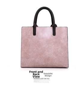 Detailed view of pink tote bag featuring smooth leather texture and brown rolled handles