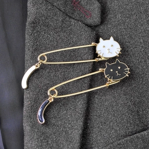 Detail of cute black and white enamel cat pins with wagging tails on a grey blazer lapel