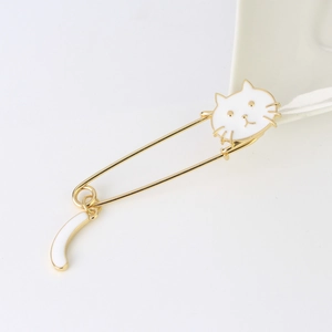 Detailed close-up of a golden cat brooch featuring a white enamel cat head and a crescent tail