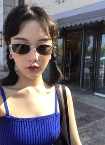 Detalle de gafas de sol cuadradas de metal plateado con lentes oscuras en una modelo