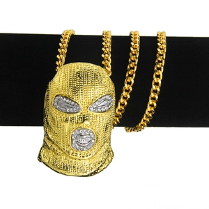Close-up of a gold hip hop balaclava pendant with crystals on a black velvet stand