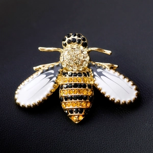 Sparkling crystal bee brooch in gold tone with white enamel wings on black leather
