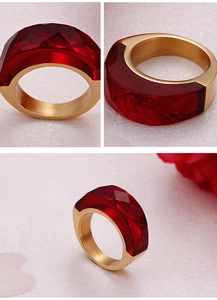 Dettagli macro di un anello largo in acciaio dorato con pietre di cristallo rosso