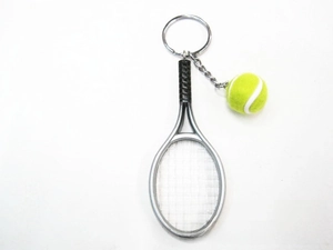 Detailed close-up of a silver tennis racket keychain with a yellow mini tennis ball
