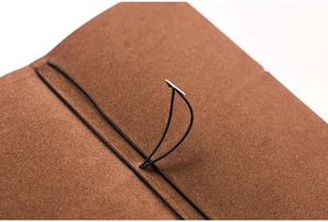 Close-up of brown textured leather notebook cover with a black elastic binding strap