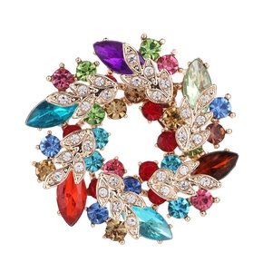 Detailed close-up of a vintage golden wreath brooch with colorful rhinestones and leaf texture