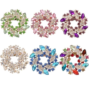 Flat lay of six colorful crystal floral wreaths brooches in gold finish on white background