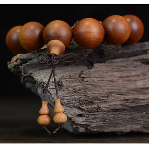 Macro shot of natural sandalwood prayer beads on aged wood with traditional Chinese knot