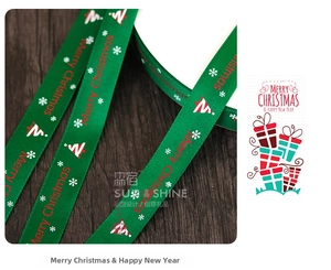 Macro shot of 2cm Merry Christmas ribbon with snow patterns on green satin fabric