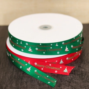 Merry Christmas satin ribbons in red and green with snowflake patterns on wood background