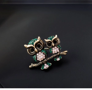 Detailed macro view of vintage bronze double owl brooch with colored rhinestones on black leather
