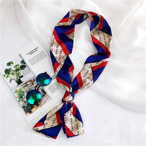 Detail shot of a long beige silk scarf with red and blue stripes and TAO TAO letter print