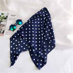 Detailed view of navy blue polka dot silk scarf draped with sunglasses for elegant styling