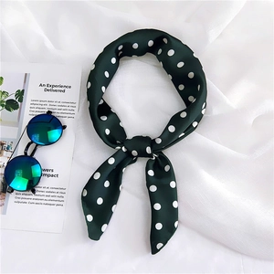 Detail of dark green polka dot silk scarf tied on white linen with stylish blue sunglasses
