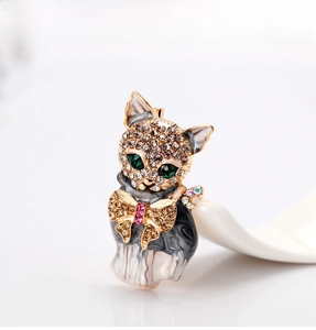 Detailed close-up of a cat brooch with green gem eyes and marbled enamel texture