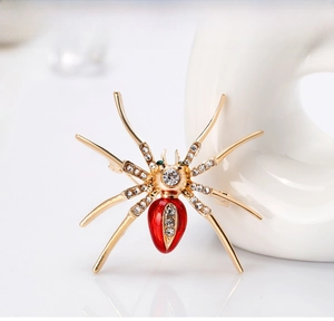 Detailed macro shot of a gold spider brooch with red belly and sparkling white crystals