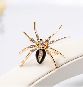 Macro detail of a gold spider brooch featuring black enamel and sparkling rhinestones