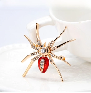 Detailed close-up of a spider brooch featuring sparkling white rhinestones and red enamel