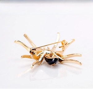 Detailed view of fashion spider brooch with gold metal legs and black stone inlay