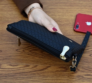 Close-up of black woven pattern clutch with double gold zippers and wrist strap detail