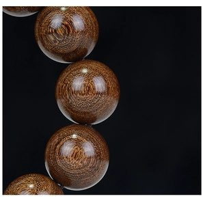 Close-up of aged sandalwood prayer beads showing golden silk texture and oily finish