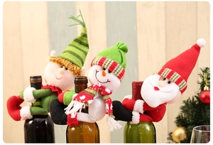 Detailed view of plush Santa and Snowman wine bottle covers with scarf on wooden table
