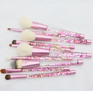 Detailed view of pink makeup brushes with liquid glitter flowing in transparent handles