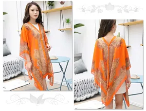 Detail view of orange bohemian chiffon shawl with intricate floral print and tassels