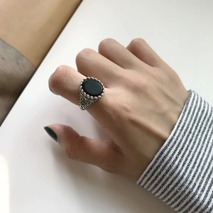 Detail of vintage S925 silver ring with black onyx and ornate engraved textures on finger
