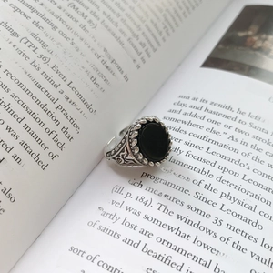 Macro detail of vintage S925 silver ring with black onyx and ornate vine carvings