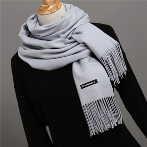 Close-up of soft cashmere texture and tassel detail on light grey winter scarf