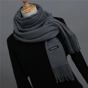 Close-up of charcoal grey cashmere scarf with soft tassels and woven logo label