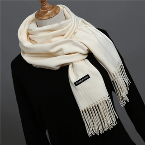 Macro shot of off-white cashmere scarf with long fringe details and woven texture
