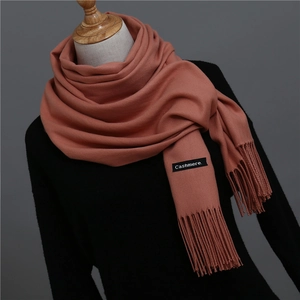 Detail of coral pink cashmere scarf showing fine diagonal weave and soft fringe tassels